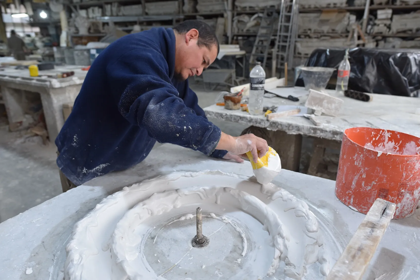 Artesano volcando yeso líquido en un molde circular