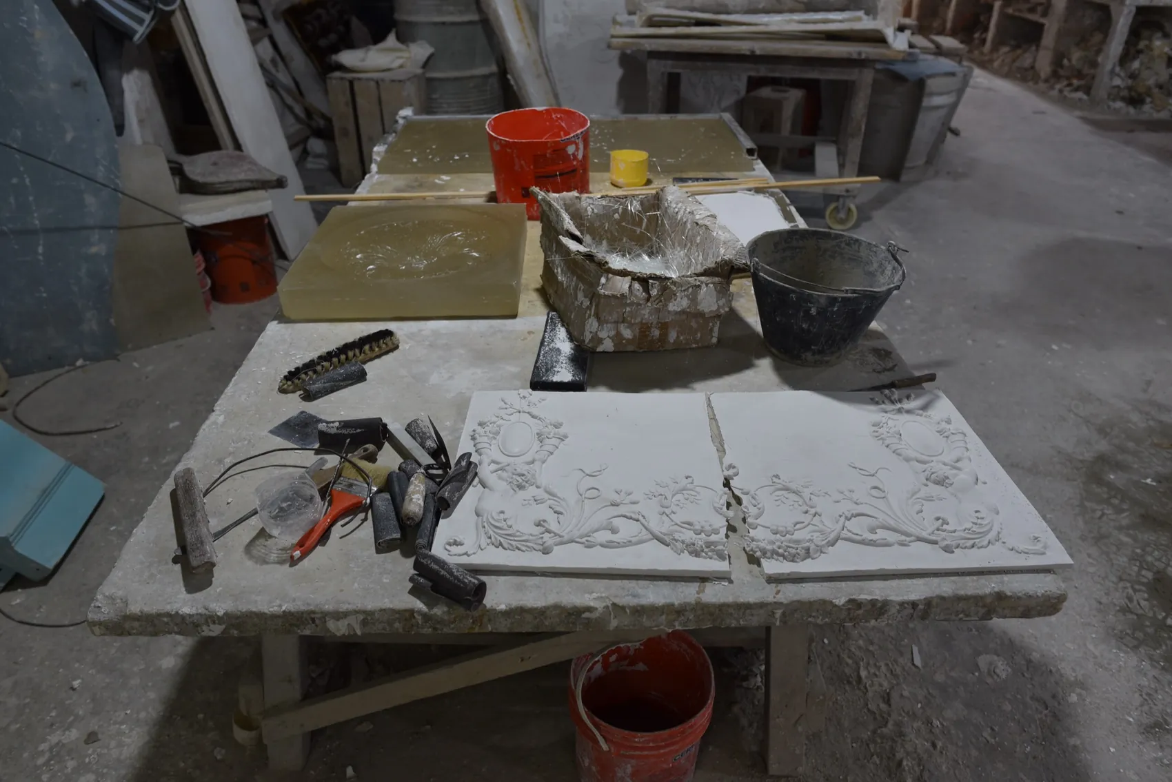 Placas con relieve de guirnaldas sobre la mesa, junto a un molde y las herramientas
