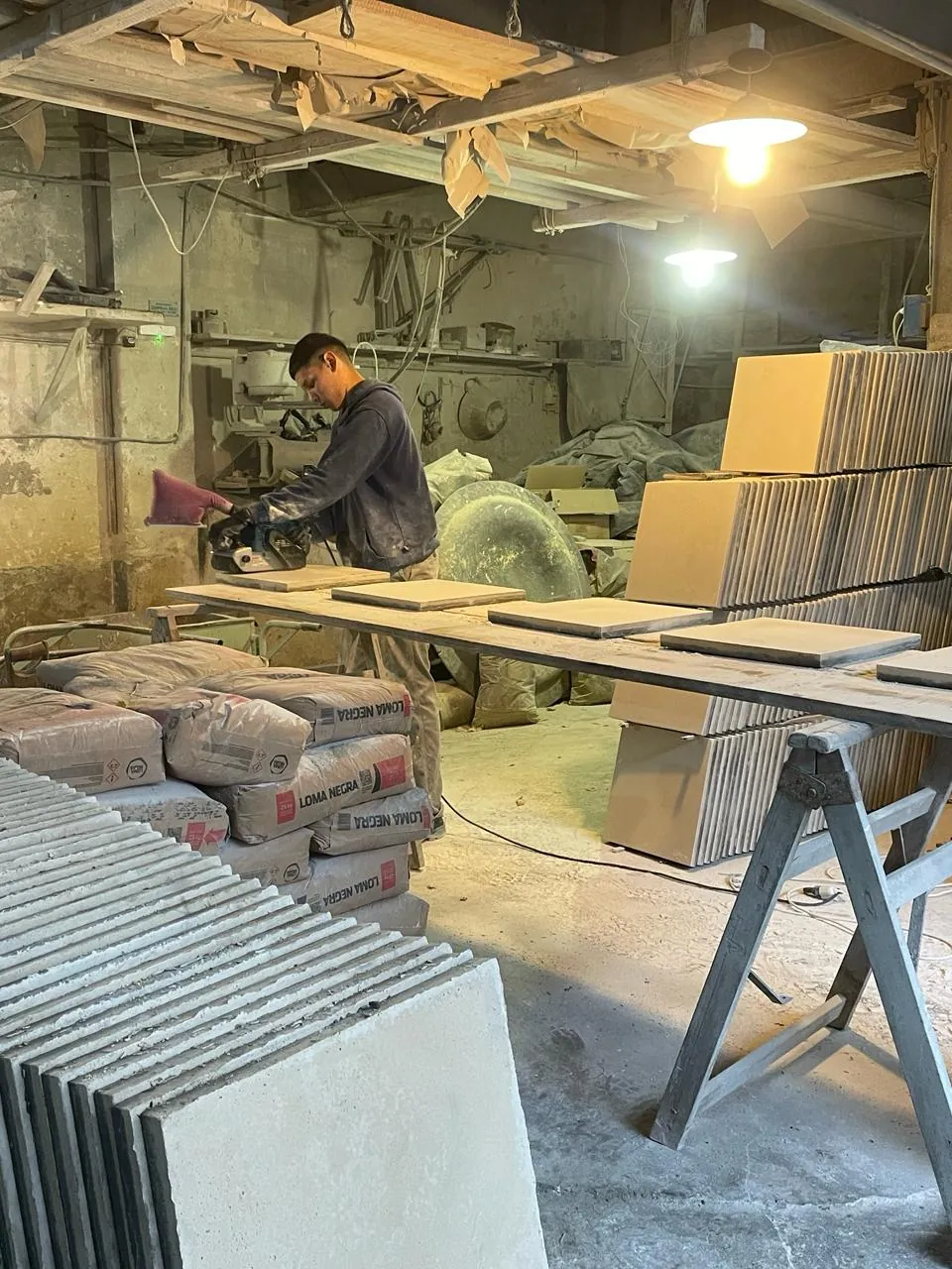 Trabajador lijando placas con una lijadora de banda
