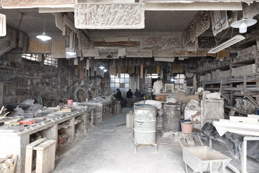 Interior del taller con mesas de trabajo y molduras talladas